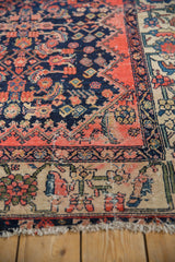 Corner view of a vintage Malayer carpet's worn knots and reciprocating floral border.