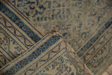 Tattered corner of vintage Caucasian rug with foundation wear and faded indigo patterns.