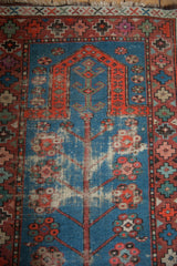 Top section of vintage Caucasian rug with indigo prayer mehrab, geometric border, and evident foundation wear.