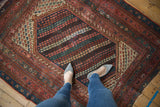 Hand knotted vintage Kurdish rug with feet, revealing varying red, teal, and navy tones.