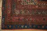 Vintage Kurdish rug corner showing dusty teal, ruby red borders with geometric motifs and fringe.