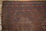 Antique Qashqai rug corner detail with madder red field, indigo borders, and visible foundation wear.