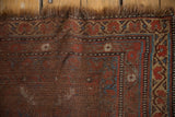 Antique Qashqai rug detail: madder red field, indigo, dusty gold border, visible worn pile.
