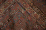 Antique Qashqai carpet close-up, revealing wear, visible foundation, and madder red hues.