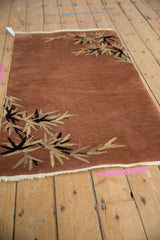 Art Deco rug's rust field with black and ivory eucalyptus leaf corner design.