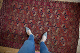 Vintage Turkmen rug with geometric gul and pomegranate border in madder red, navy, and ivory.