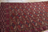 Worn geometric floral guls and lattice side border of a vintage Turkmen rug, madder red, navy, ivory.