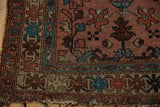 Vintage Lilihan rug corner with secure fringe, colorful crab-pattern border, and dusty rose field.