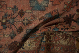 Dusty rose and blue patterns on the worn, hand-knotted pile of a Lilihan rug.