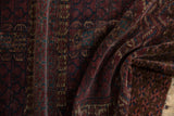 Folded vintage Turkmen rug with intricate deep wine, navy, and ivory geometric patterns, worn.