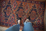 Antique Caucasian Soumac rug's intricate geometric patterns in chestnut, navy, and fuchsia, underfoot.
