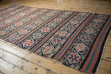Intricate geometric patterns in alternating bands of navy, terracotta, and ivory on this antique Caucasian kilim.