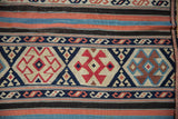 Kuba Kilim flatweave with navy serpent motifs and parallel terracotta, black, and blue stripes.
