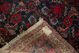 Vintage Hamadan rug's hand-knotted back, fringe, and label, with navy and red Herati motif.
