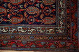 Vintage Hamadan rug corner with navy boteh pattern, ivory geometric border, and red fringe.