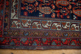 Vintage Hamadan rug corner, showcasing complex geometric border patterns in navy, red, and ivory.