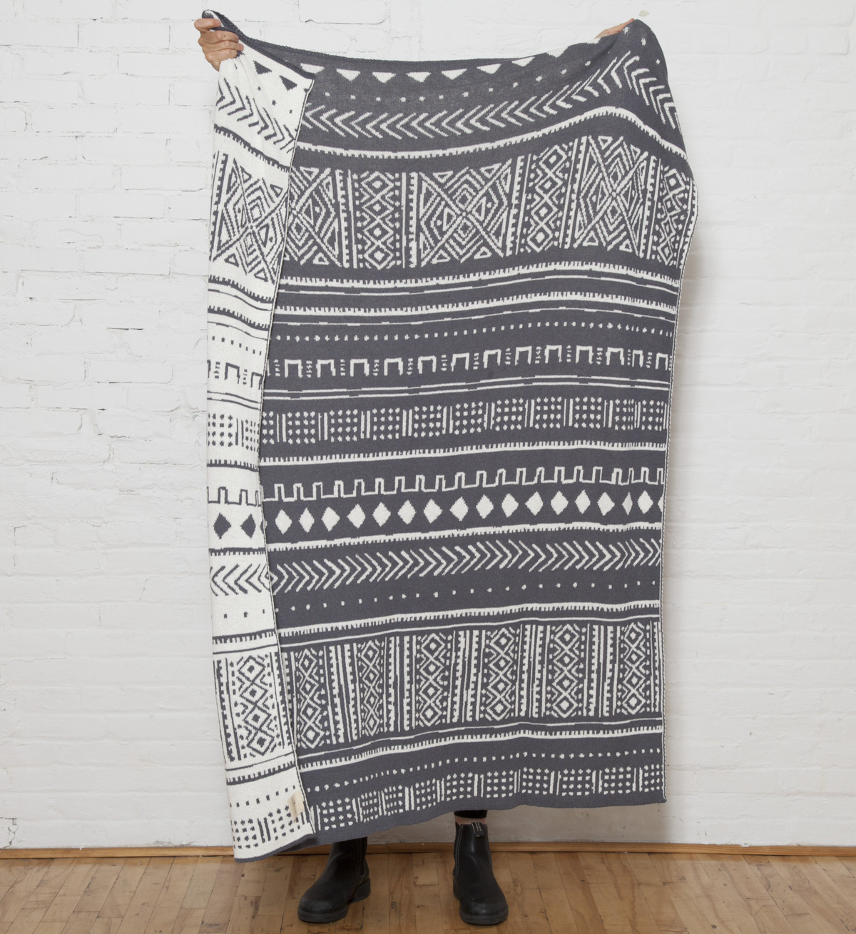 Reversible gray and white knit blanket with mudcloth geometric design, 50x60 inches.
