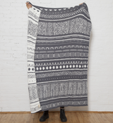 Reversible gray and white knit blanket with mudcloth geometric design, 50x60 inches.