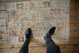 A full view of the distressed Oushak rug's low pile and visible foundation.