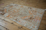 Distressed corner of a vintage Oushak rug showing coffee brown and pale tangerine orange tones.