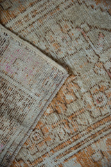 Corner detail of a distressed Oushak rug showing the hand-knotted reverse and worn, low pile.