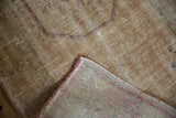 Distressed Oushak rug pile with exposed foundation and a dusty raspberry selvedge edge.