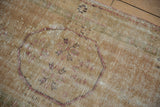 Distressed Oushak rug corner showing worn pile, visible foundation, and original selvage.