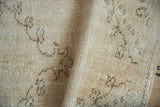 Vintage Distressed Oushak rug's cream pile showing mostly even wear and faded bud patterns.