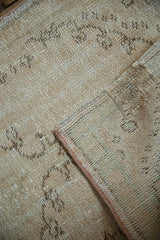 Distressed Oushak rug close-up showing mostly even wear and intact side cord selvage.