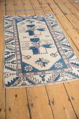 Distressed Oushak rug showing finned geometric floral motifs in ivory, denim blue, and pale mauve.