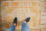 Distressed hand-knotted Oushak rug's saffron yellow and tangerine geometric pattern detail.