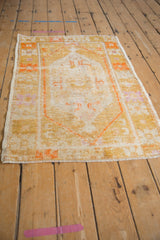 Distressed Oushak rug corner, showing geometric border, fringe, and worn pile.