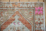 Vintage Oushak rug corner, geometric border with hot pink, rust, and distressed beige pile.