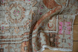 Distressed Oushak rug texture, showing hot pink pops, rust, and beige geometric designs with worn pile.
