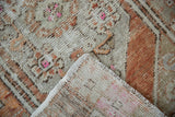 Distressed Vintage Oushak rug pile with beige, rust, hot pink hues, and visible selvage.