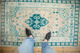 Distressed Oushak rug with soft abrash and visible pinwheel floral motifs in teal and ivory.