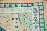 Dusty teal and beige starburst border and geometric patterns on a distressed Oushak rug.