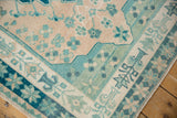 Distressed Oushak rug corner, showing outer starburst border in deep green and teal.