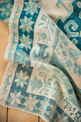 Distressed Oushak rug texture with diluted teal, green, ivory pinwheel floral motifs.