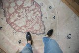 Vintage distressed Oushak carpet with dusty mauve and ivory patterns underfoot.