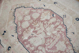 Close-up of distressed Oushak carpet pile showing aubergine florals and striations.