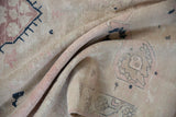 Distressed Oushak carpet texture with soft beige, mauve, navy hues and visible striations.