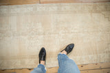 Distressed vintage Oushak runner with faded ivory floral motifs and light abrashed field.