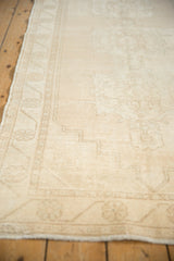 Distressed vintage Oushak rug runner, showing muted ivory tones and faded floral texture.