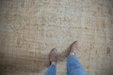 Distressed vintage Oushak carpet in pale coffee and ivory tones, displaying faded floral motifs and worn texture.