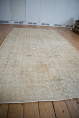 Textured distressed vintage Oushak carpet with visible foundation and light edge.