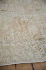 Distressed vintage Oushak carpet close-up, revealing worn pile and exposed foundation.