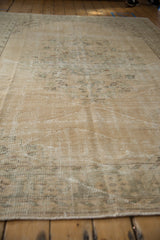 Distressed Oushak carpet close-up, showing low pile texture and visible foundation.