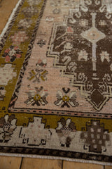 Distressed Oushak runner: textured pile in olive green border, dusty blush field, nuanced floral motifs.