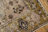 Distressed Oushak runner corner, textured pile, visible foundation, and blush, olive border design.